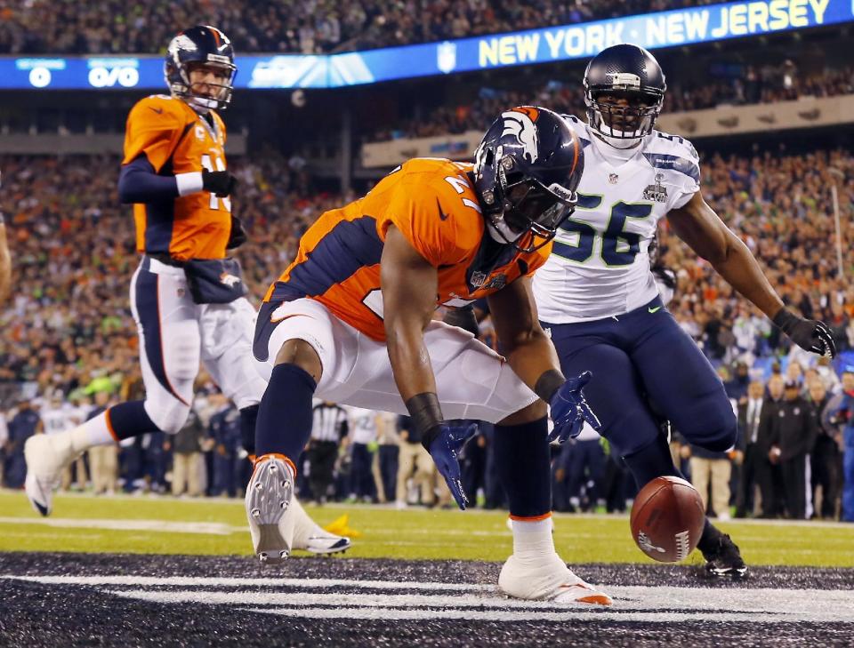 Denver Broncos' Knowshon Moreno reaches for a loose ball after the snap passed teammate Peyton Manning, left, during the first half of the NFL Super Bowl XLVIII football game Sunday, Feb. 2, 2014, in East Rutherford, N.J. Seattle Seahawks' Cliff Avril approached at right. (AP Photo/Paul Sancya)