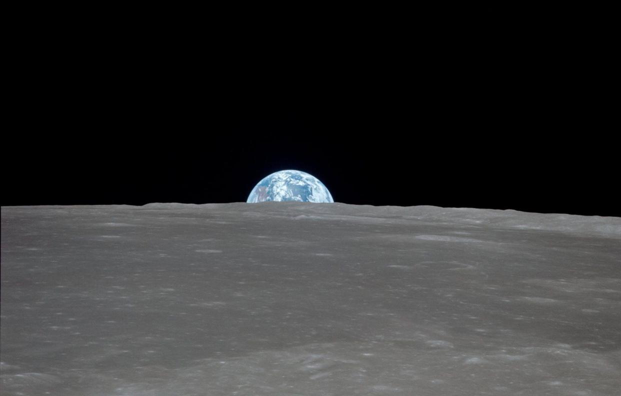 the crescent Earth as it rises above the lunar horizon