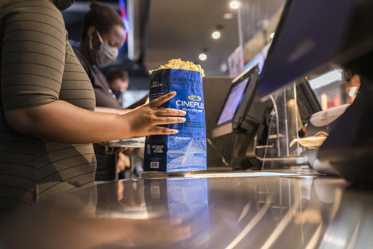 Cineplex employees serve customers popcorn and other snacks behind a plastic barrier, at a Cineplex theatre in downtown Toronto on Wednesday, Aug. 26, 2020. THE CANADIAN PRESS/Christopher Katsarov