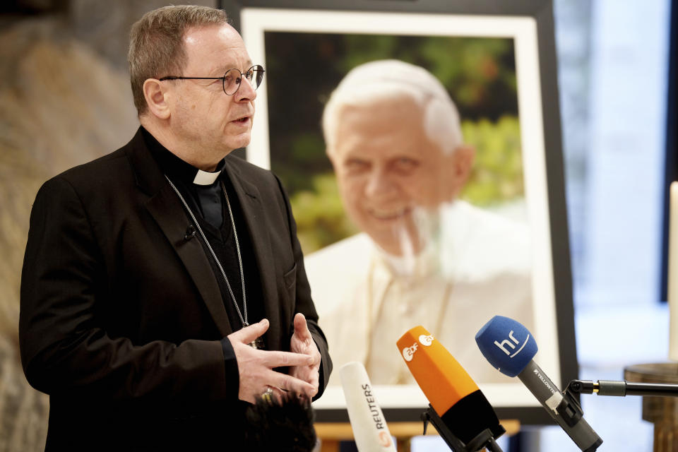 Bishop Georg Baetzing, head of the German Bishops' Conference, addresses the media as he stands next to a portrait of Pope Emeritus Benedict XVI during a statement in Limburg, Germany, Saturday, Dec. 31, 2022. Pope Emeritus Benedict XVI, the German theologian who will be remembered as the first pope in 600 years to resign, has died, the Vatican announced Saturday. He was 95. (Thomas Frey/dpa via AP)