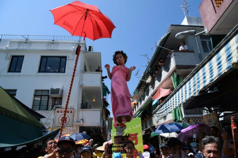 Hailey Miu (C), aged four, stands on a float while portraying a landlady from Stephen Chow's movie "Kung Fu Hustle" during the annual Cheung Chau bun festival