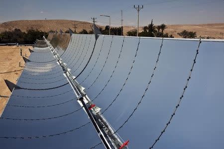 A worker stands next to parabolic mirrors tracking the sun at the research site of solar power company Brenmiller Energy in Israel's Negev desert, near the town of Dimona in this file photo taken on September, 9, 2014. REUTERS/ Nir Elias