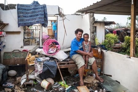 Fijian woman Kalisi holds her son Tuvosa, 3, as she sits on a bed in the remnants of her home damaged by Cyclone Winston in the Rakiraki District of Fiji's Ra province, in this February 24, 2016 handout picture provided by UNICEF. REUTERS/UNICEF-Sokhin/Handout via Reuters