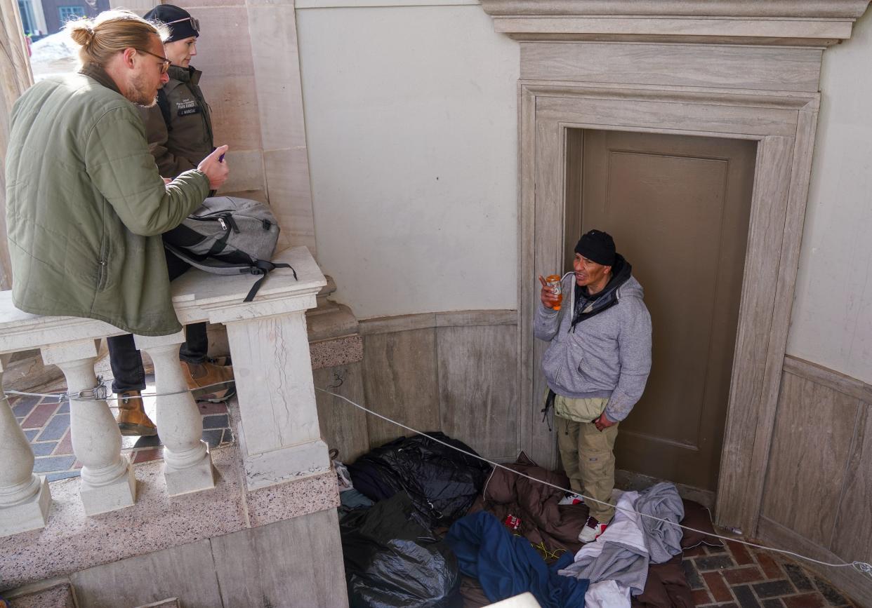 Tom Kaiser, a mental health clinician with WellPower, and Denver park ranger Jodie Marozas, speak with an unhoused man who gave his name as both "Richard" and "Tony" in a closed area of a city park.