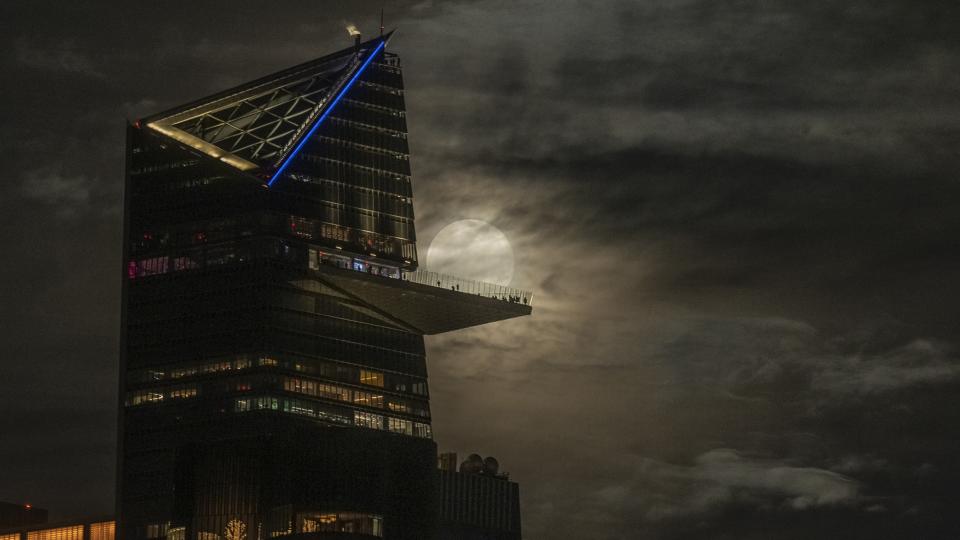 clouded snow moon behind a balcony and large building