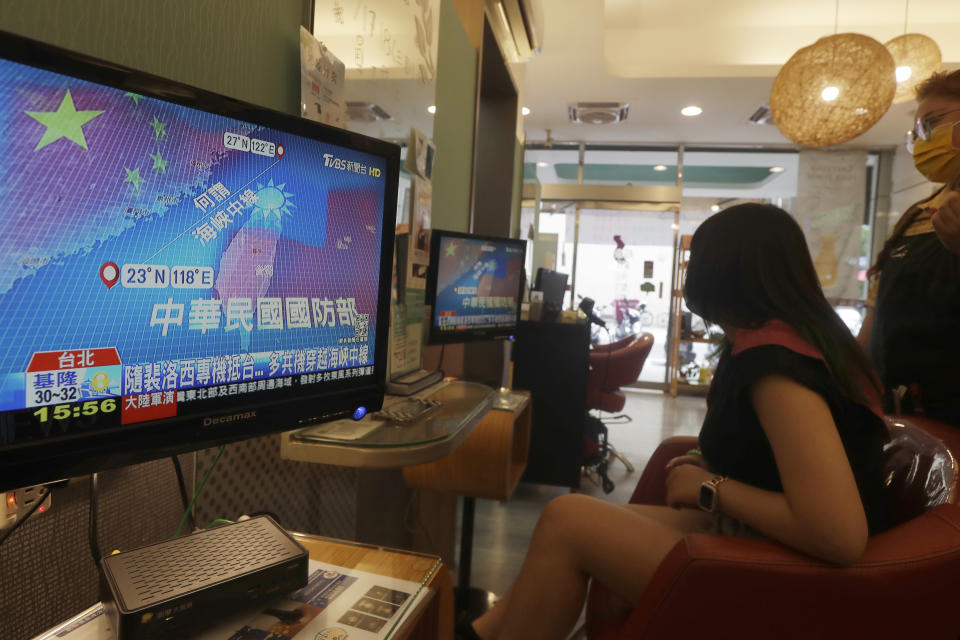 A customer and a staff member watch a news report on U.S. House of Representatives Speaker Nancy Pelosi's visit to Taiwan, at a beauty salon in Taipei, Taiwan, Thursday, Aug. 4, 2022. Taiwan canceled airline flights Thursday as the Chinese navy fired artillery near the island in retaliation for a top American lawmaker’s visit. (AP Photo/Chiang Ying-ying)