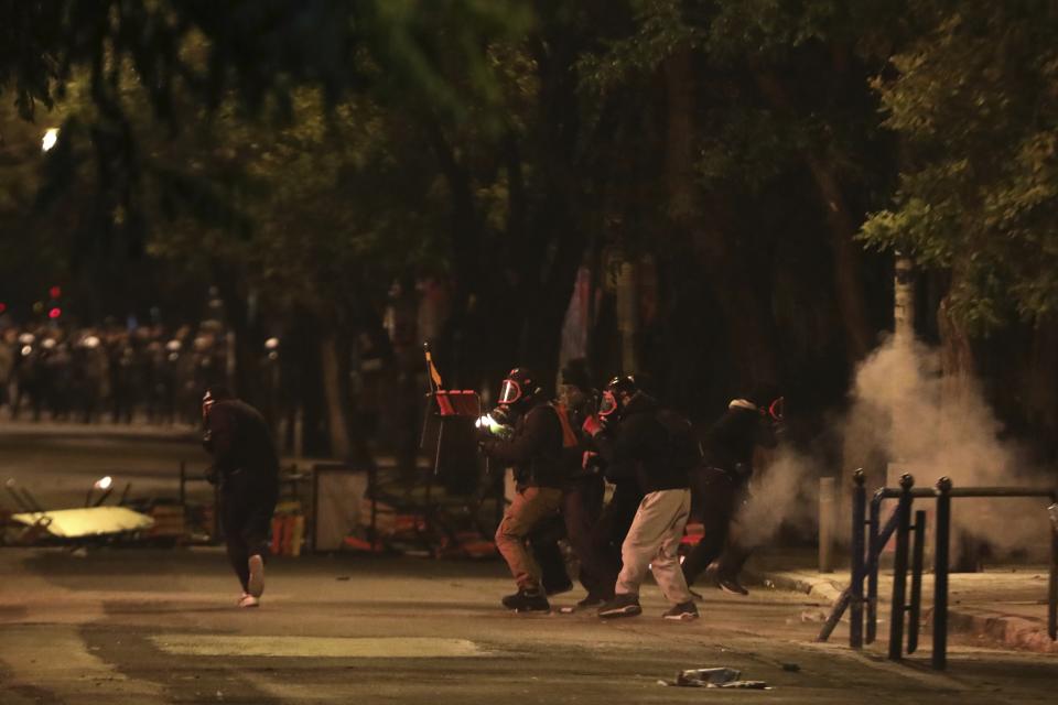 Protesters prepare to throw a petrol bomb and a chair at riot police during clashes in the Athens neighborhood of Exarchia, a haven for extreme leftists and anarchists, Saturday, Nov. 17, 2018. Clashes have broken out between police and anarchists in central Athens on the 45th anniversary of a student uprising against Greece's then-ruling military regime. (AP Photo/Yorgos Karahalis)