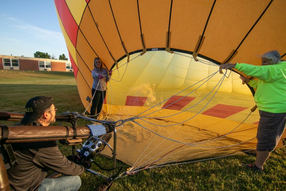 Heather Jones-Harder, left, and Patty Cramer hold the balloon Overheat open as pilot Phil Clinger of Battle Creek ignites a burner to heat the air previously blown inside as a number of balloons launch for the media Friday, June 24, 2022 at the Howell High School campus.