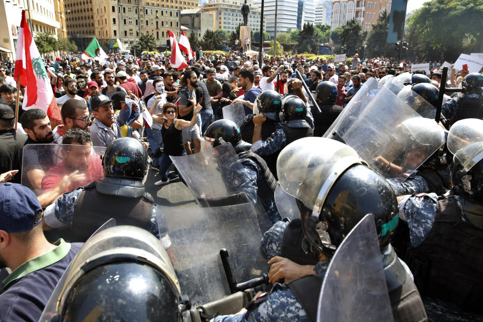 Lebanese anti-government protesters clash with riot policemen as they try to cross to the government house during a demonstration, in downtown Beirut, Lebanon, Sunday, Sept. 29, 2019. Hundreds of Lebanese are protesting an economic crisis that has worsened over the past two weeks, with a drop in the local currency for the first time in more than two decades. (AP Photo/Bilal Hussein)