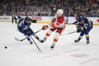 Calgary Flames' Blake Coleman (20) passes as St. Louis Blues' Pavel Buchnevich (89) and Jake Neighbours (63) defend during the second period of an NHL hockey game Thursday, March 28, 2024, in St. Louis. (AP Photo/Jeff Roberson)