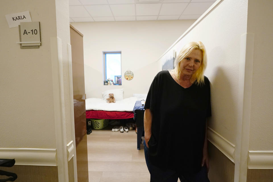 Karla Finocchio, 55, poses for a photo in her new apartment at Ozanam Manor temporary housing for people 50 and up seeking permanent housing, Friday, Feb. 4, 2022, in Phoenix. Finocchio is one face of America's graying homeless population, a rapidly expanding group of destitute and desperate people 50 and older suddenly without a permanent home after a job loss, divorce, family death or health crisis during a pandemic. (AP Photo/Ross D. Franklin)