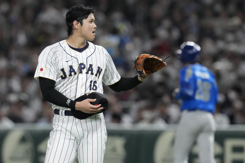 Shohei Ohtani of Japan holds his cap as Italy's Ben DeLuzio walks to first base after being hit by a pitch during the fifth inning of the quarterfinal game between Italy and Japan at the World Baseball Classic (WBC) at Tokyo Dome in Tokyo, Japan, Thursday, March 16, 2023. (AP Photo/Eugene Hoshiko)