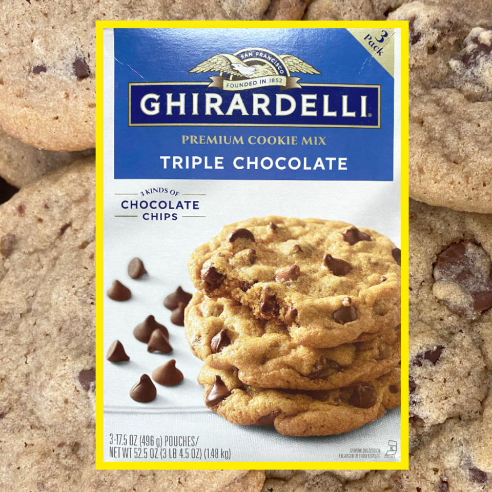 Ghirardelli Triple Chocolate Premium Cookie Mix package placed on a pile of baked chocolate chip cookies. The package shows a photo of stacked cookies