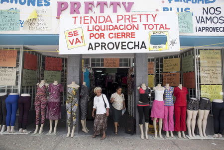 Women leave a clothing store with a big sign reading "Store Pretty, total closing down sale, take advantage" in Arecibo, Puerto Rico, June 29, 2015. REUTERS/Alvin Baez-Hernandez