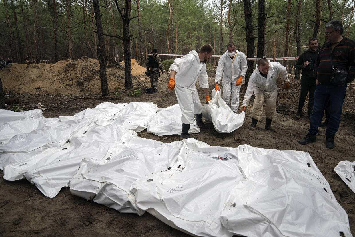 Experts work during the exhumation of bodies in the recently retaken area of Izium, Ukraine, Friday, Sept. 16, 2022. Ukrainian authorities discovered a mass burial site near the recaptured city of Izium that contained hundreds of graves. It was not clear who was buried in many of the plots or how all of them died, though witnesses and a Ukrainian investigator said some were shot and others were killed by artillery fire, mines or airstrikes. (AP Photo/Evgeniy Maloletka)