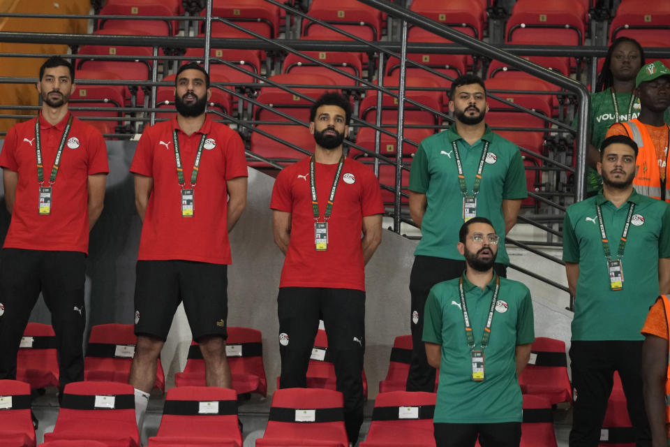 Egypt's injured player Mohamed Salah, centre, stands on the bench before the African Cup of Nations Group B soccer match between Cape Verde and Egypt at the Felix Houphouet Boigny stadium in Abidjan, Ivory Coast, Monday, Jan. 22, 2024. (AP Photo/Themba Hadebe)