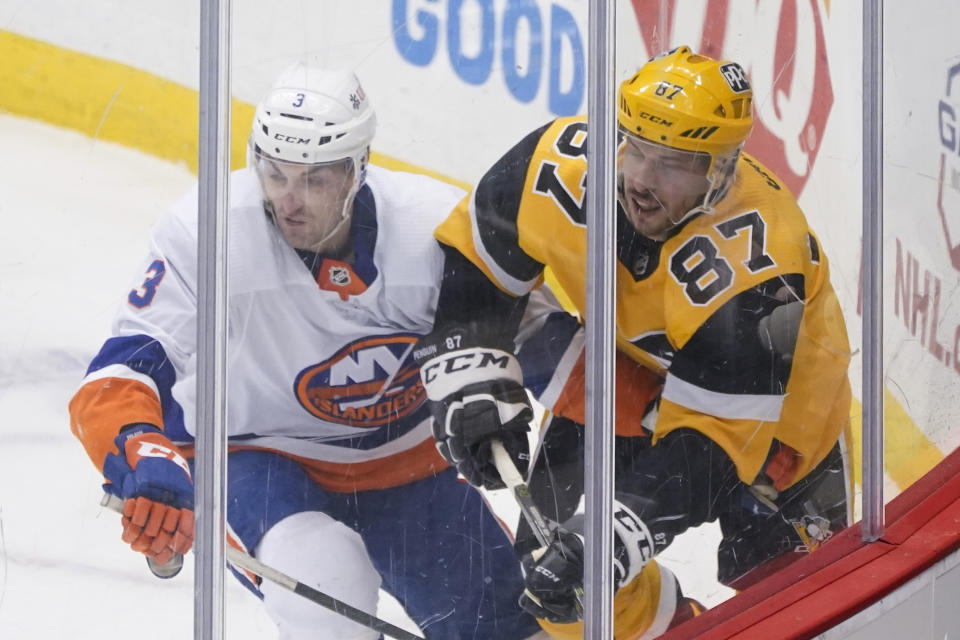 Pittsburgh Penguins' Sidney Crosby (87) and New York Islanders' Adam Pelech (3) work in the corner during the first period of an NHL hockey game Saturday, March 27, 2021, in Pittsburgh. (AP Photo/Keith Srakocic)