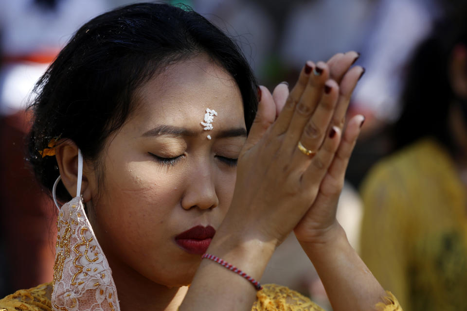 A Balinese woman prays at a temple amid concerns of the new coronavirus outbreak during a Hindu ritual in Bali, Indonesia Saturday, July 4, 2020. (AP Photo/Firdia Lisnawati)