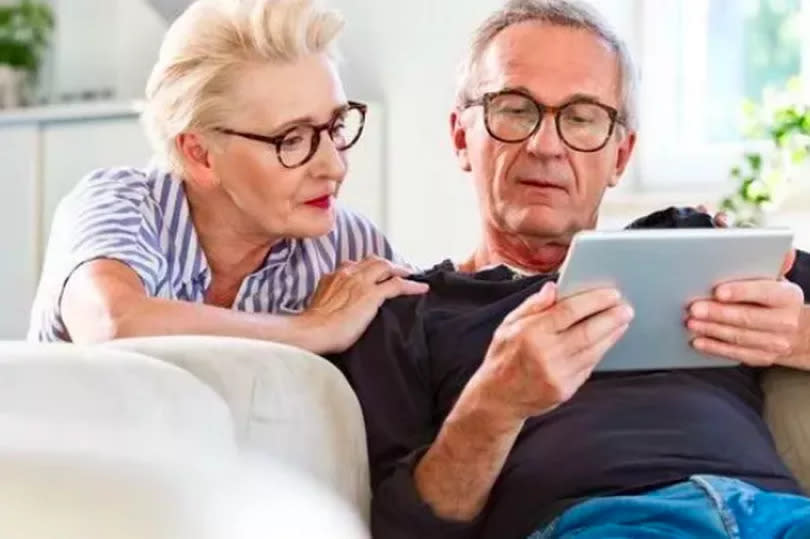 A smiling mana and woman are looking at a tablet screen