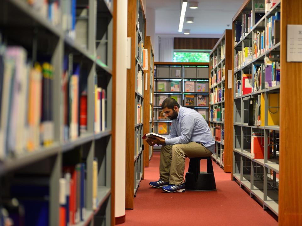 A man sits and reads in a library.