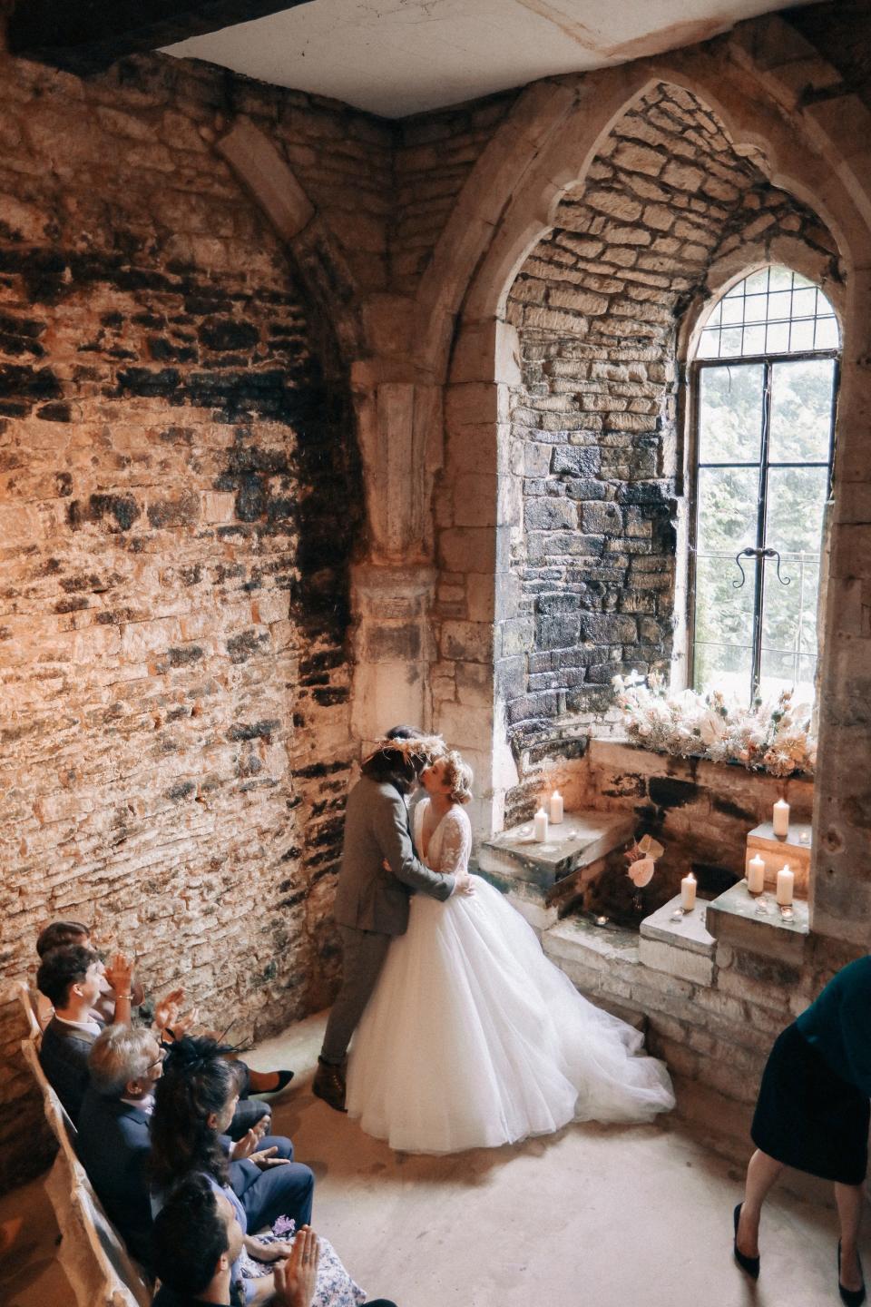 A couple kisses during their wedding ceremony in a church.