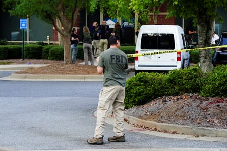 An FBI evidence response team agent cordons off an entrance to an office park as federal agents execute search warrants on multiple businesses in Lawrenceville