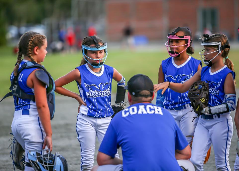 Firestorm coach Ryan Hemphill talks with his pitcher Sophia Almeida, catcher Zoey Hemphill, and infielders Mackenzie Lee, and Lexi Pequita during a visit to the mound.