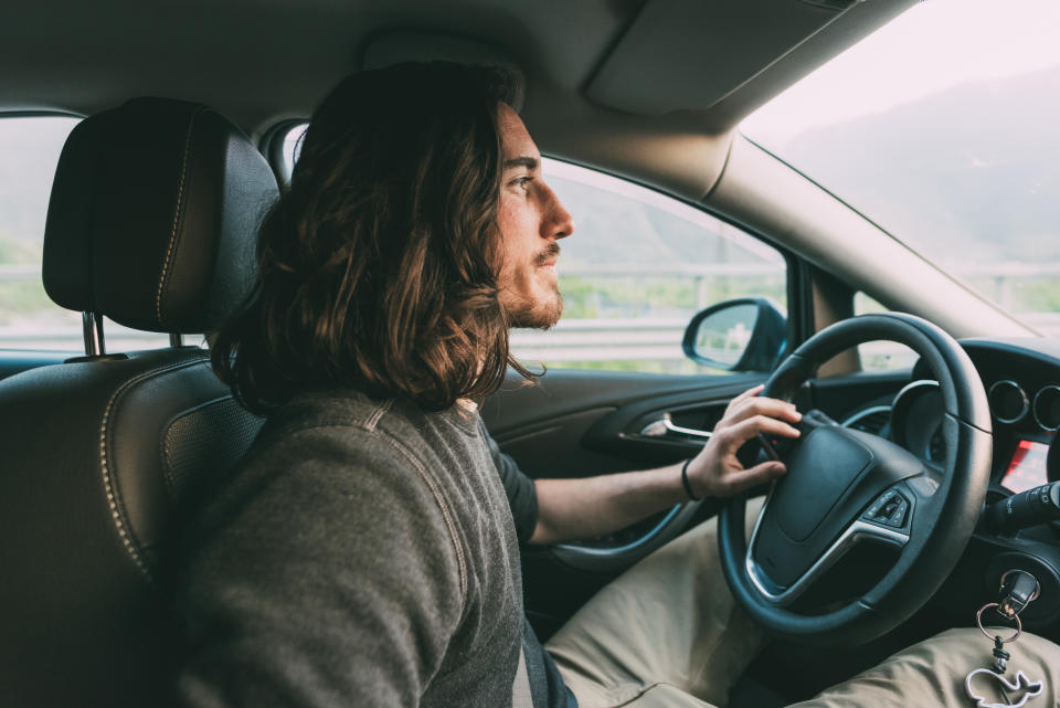 A young man is driving a car