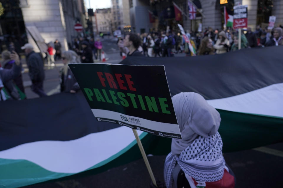 Protesters hold flags and placards as they take part in a pro-Palestinian demonstration in London, Saturday, Nov. 25, 2023. (AP Photo/Alberto Pezzali)