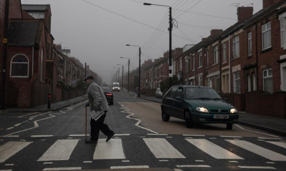 A man with a stick walks across a zebra crossing on a grey day in Stanley, Durham – a county that voted for Brexit.