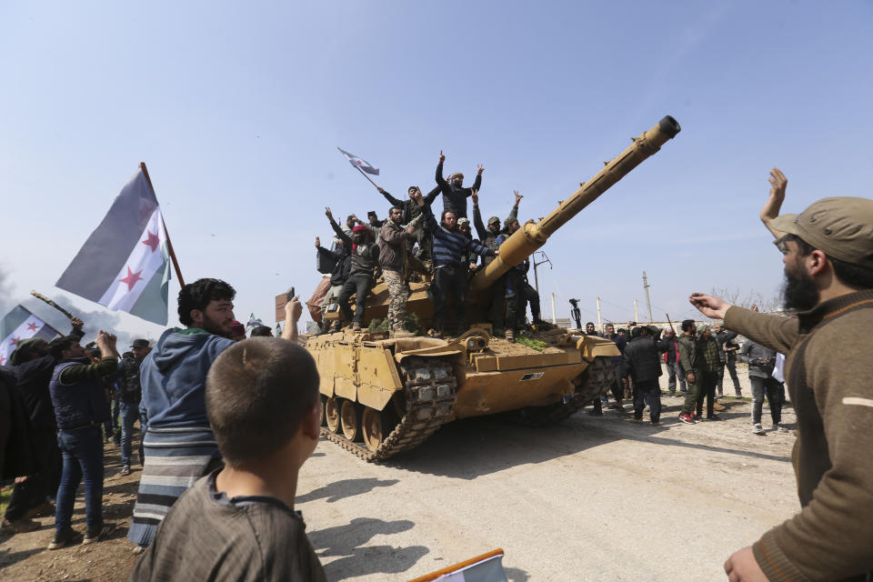 Syrians climb on a Turkish tank in Neyrab, Sunday, March 15, 2020 as they protest agreement on joint Turkish and Russian patrols in northwest Syria. Patrols on the M4 highway, which runs east-west through Idlib province, are part of a cease-fire agreed between Turkey and Russia after an escalation in fighting that saw the Turkish military in direct conflict with Syrian government troops.( (AP Photo/Ghaith Alsayed)