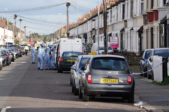 Forensic investigators in blue suits standing in the middle of a residential street.