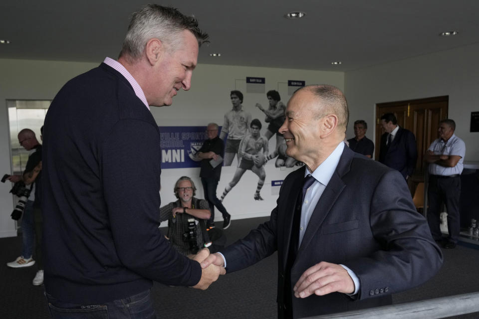 Australian rugby union head coach Eddie Jones, right, shakes hands with former Wallaby Justin Harrison at Matraville Sports High School in Sydney, Tuesday, Jan. 31, 2023. Jones, who was named as new coach of the Australian rugby team on Jan. 16, faced the media on Tuesday in his first appearance since returning to the Wallabies. He will lead the team at the Rugby World Cup later this year in France. (AP Photo/Rick Rycroft)