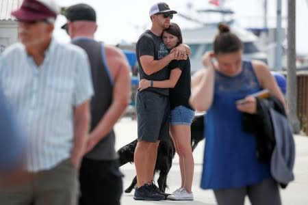 Two people hug as they look over a makeshift memorial near Truth Aquatics as the search continues for those missing in a pre-dawn fire that sank a commercial diving boat near Santa Barbara, California