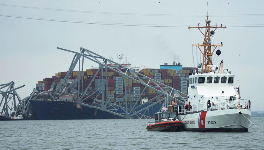 A Coast Gaurd cutter patrols in front of a cargo ship that is stuck under the part of the structure of the Francis Scott Key Bridge after the ship hit the bridge Wednesday March 27, 2024, in Baltimore, Md. (AP Photo/Steve Helber)