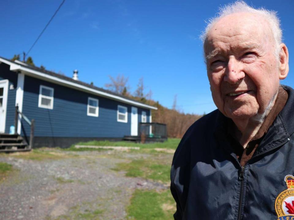 Charlie Comrie stands outside his new home in Plate Cove West, a rural community in Newfoundland. The Second World War vet moved there in December 2021 from southern Ontario.  (Melissa Tobin/CBC - image credit)