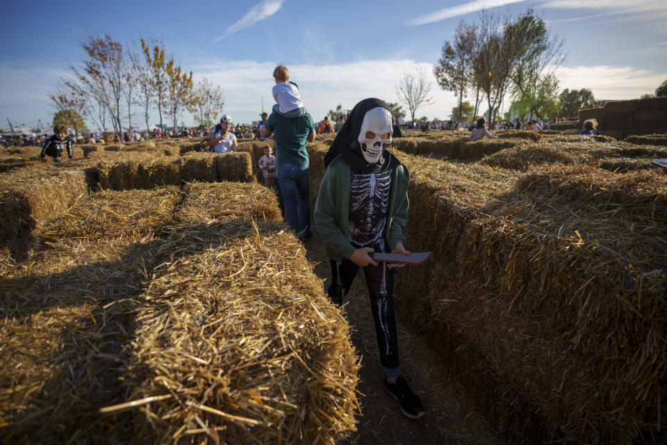 A child wearing a costume walks in a labyrinth made of hay bales at the West Side Hallo Fest, a Halloween festival in Bucharest, Romania, Saturday, Oct. 28, 2023. Tens of thousands streamed last weekend to Bucharest's Angels' Island peninsula for what was the biggest Halloween festival in the Eastern European nation since the fall of Communism. (AP Photo/Andreea Alexandru)