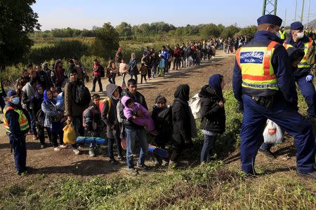 Migrants queue to board a train at the railway station in Zakany, Hungary October 1, 2015. REUTERS/Bernadett Szabo