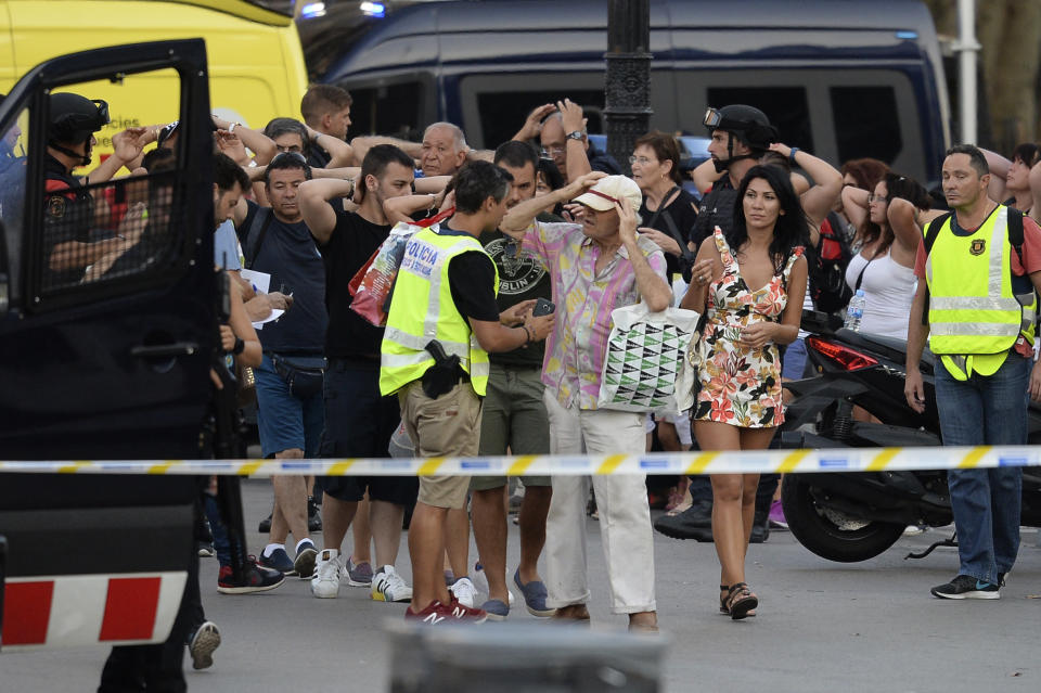 People put their hands up as police check their identities near the scene of the attack.