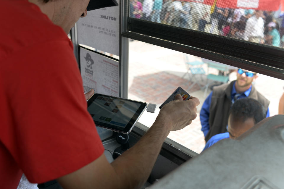 DENVER, CO - JUNE 18: Chris Valdez with Bubba Dukes BBQ swipes a card using square system for his transaction June 18, 2015 at Civic Center Park. Food truck vendors set up for the afternoon lunch crowd at Civic Center Park. How are small businesses and entrepreneurs that use credit card readers like Square that attach to their phone or tablet handling the Oct. 1 deadline to have card readers that can handle cards with microchips. Among those affected are food truck operators. (Photo By John Leyba/The Denver Post via Getty Images)