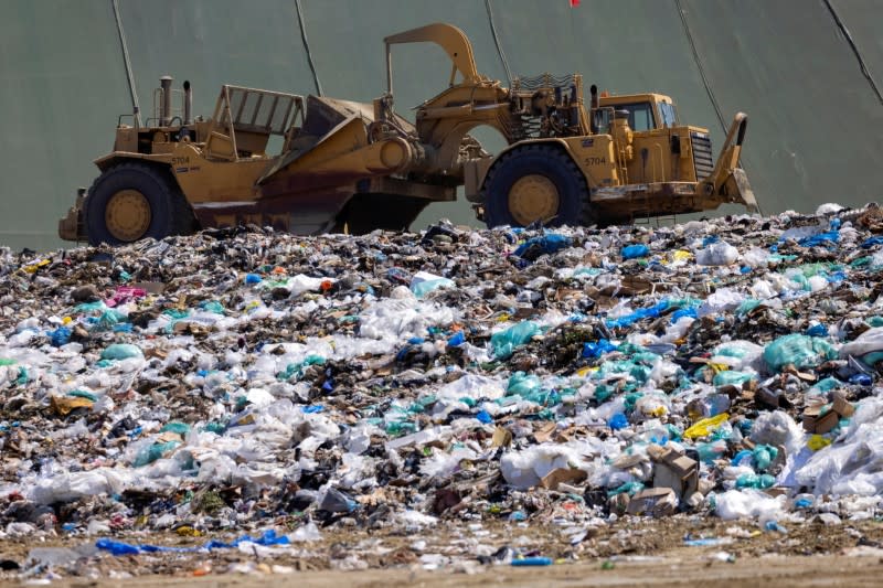 Workers use heavy machinery to move trash and waste at the Frank R. Bowerman landfill in California