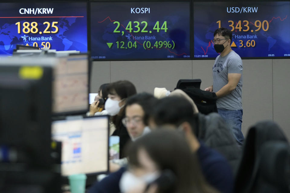 A currency trader passes by screens showing the Korea Composite Stock Price Index (KOSPI), center, and the exchange rate of South Korean won against the U.S. dollar, right, at the foreign exchange dealing room of the KEB Hana Bank headquarters in Seoul, South Korea, Monday, Nov. 21, 2022. Asian stock markets sank Monday after Wall Street ended with a loss for the week amid anxiety about Federal Reserve plans for more interest rate hikes to cool inflation. (AP Photo/Ahn Young-joon)