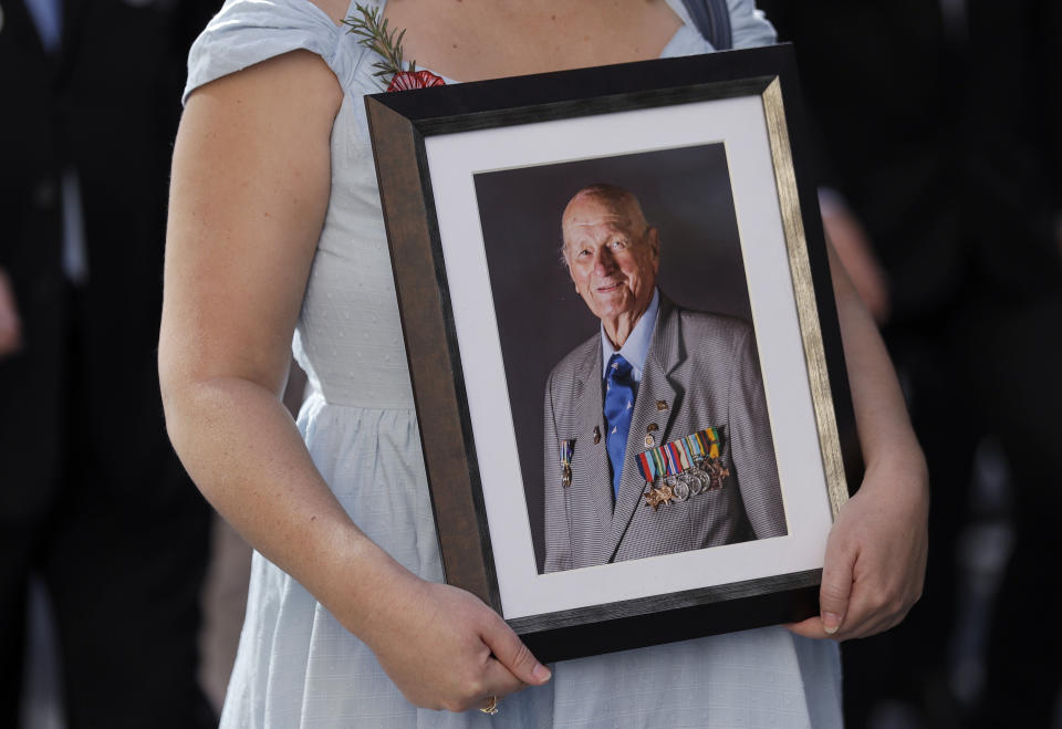 A woman carries a photo of a veteran during a march celebrating ANZAC Day, a national day of remembrance in Australia and New Zealand that commemorates those that served and died in all wars, conflicts, and while peacekeeping, in Sydney, Australia, Thursday, April 25, 2019. (AP Photo/Rick Rycroft)