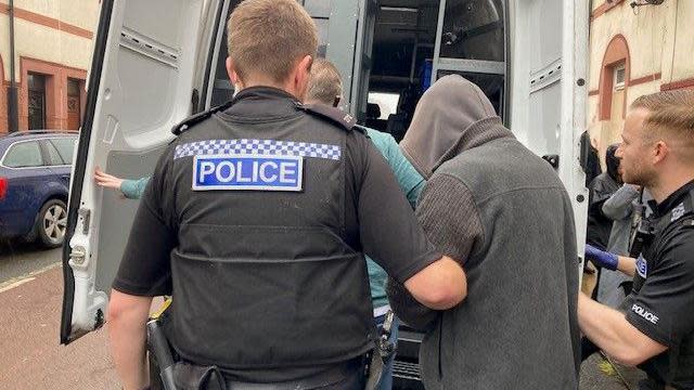 Man being put into the back of a police van