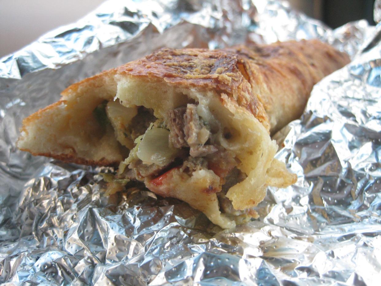 Half eaten small meat and onion pie in foil.