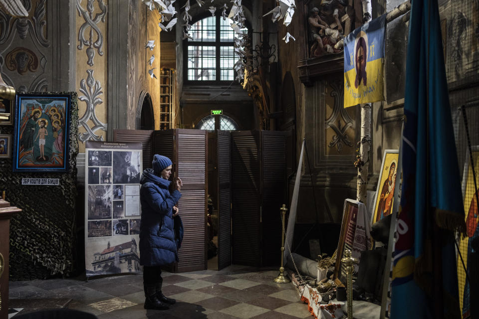 A Christian worshiper prays in front of a memorial to fallen soldiers at the Saints Peter and Paul Garrison Church in Lviv, western Ukraine, Sunday, March 6, 2022. The memorial is dedicated to Ukrainian soldiers who died after 2014. (AP Photo/Bernat Armangue)