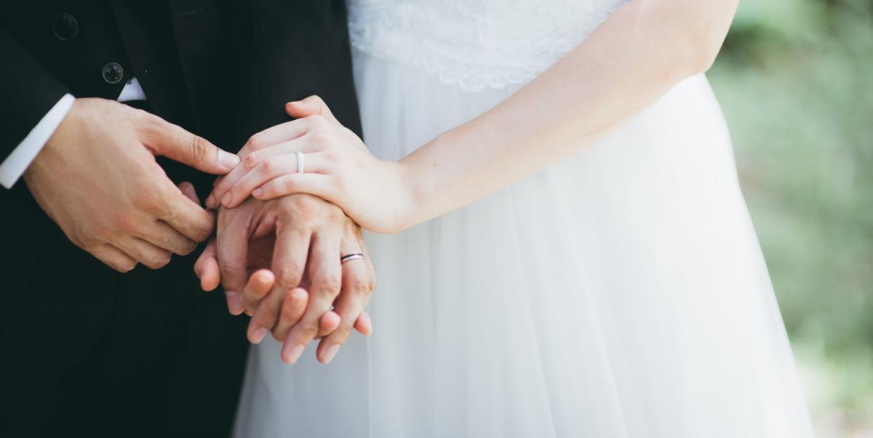 close up of wedded couple holding hands