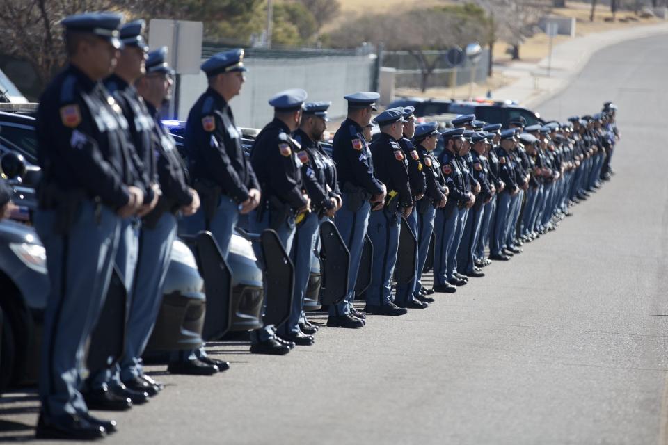 Officers stand outside in salute as the procession for the late El Paso police Chief Greg Allen passes by Mission Valley Regional Command Center.