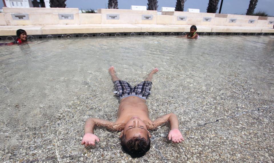 Joe Angel Martinez, 6, tries to cool off in the Bayfront Park water feature on Shoreline Boulevard in Corpus Christi despite the water jet not functioning Thursday, June 20, 2013.