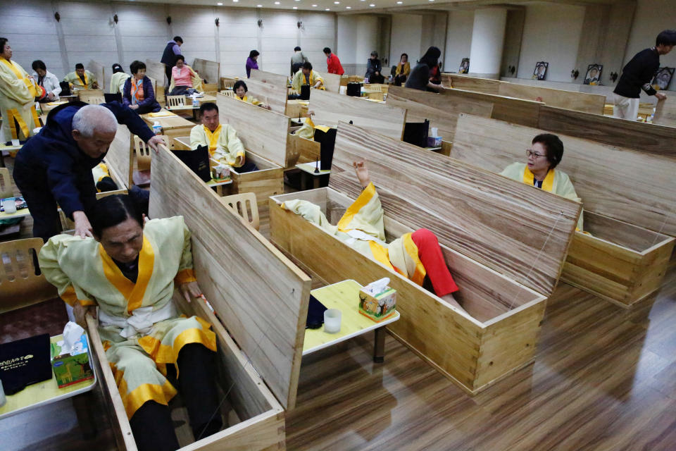 Participants get into coffins during a "living funeral" event as part of a "dying well" programme, in Seoul, South Korea, October 31, 2019. Picture taken on October 31, 2019.    REUTERS/Heo Ran